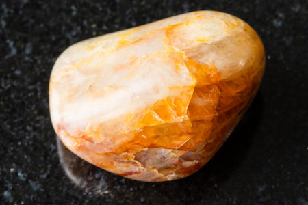 sample of polished orange quartz rock on black granite background close up from South Urals, Russiaの写真素材