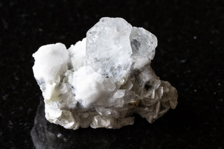 sample of rough colorless beryl (Goshenite) with mica and feldspar rock on black granite background close up from Sichuan, Chinaの写真素材