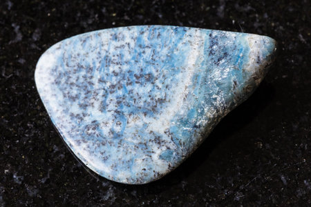 sample of tumbled rock on black granite background close upの写真素材