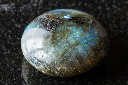 sample of polished labradorite gemstone on black granite background close up from Madagascarの写真素材