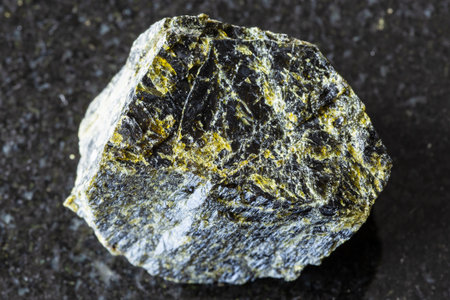 sample of rough diopside mineral on black granite background close up from Kola Peninsula, Russiaの写真素材