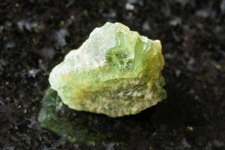 sample of rough yellow green beryl rock on black granite background close up from Tanzaniaの写真素材