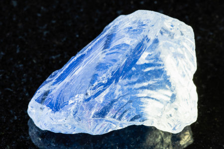 sample of rough molybdenum glass imitation of moonstone on black granite background close up from Russiaの写真素材