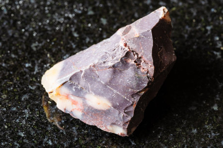 sample of raw brown mookaite mineral on black granite background close up from Australiaの写真素材