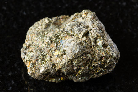 sample of rough pyrite rock on black granite background close up from Russiaの写真素材
