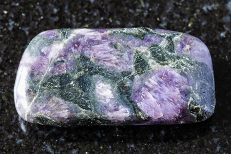 sample of tumbled kataranskite mineral on black granite background close up from Kola Peninsula, Russiaの写真素材