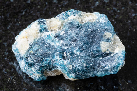sample of raw grandidierite rock on black granite background close up from Madagascarの写真素材