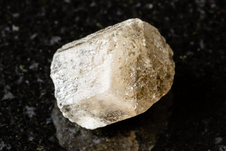 sample of raw phenakite mineral on black granite background close up from Middle Urals, Russia