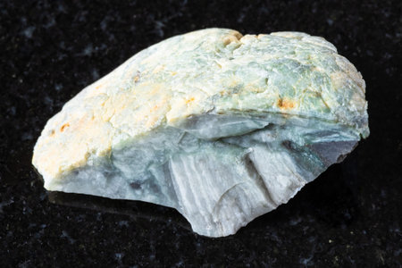 sample of raw trass chernomorite rock on black granite background close up from Crimea