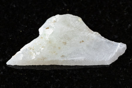 sample of rough white nephrite mineral on black granite background close up from Chinaの写真素材
