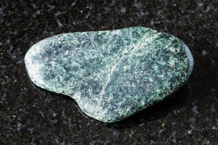 sample of tumbled actinolite rock on black granite background close up from North Karelia, Russiaの写真素材
