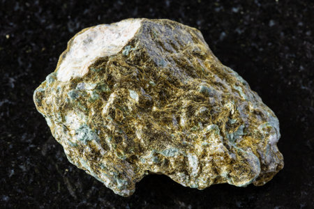 sample of raw lobanovite rock on black granite background close up from from Khibiny, Kola...
