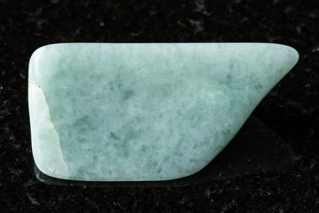 sample of polished jadeite mineral on black granite background close up from Khakassia, Russiaの写真素材