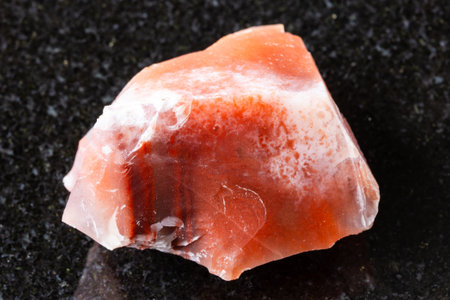 sample of raw carnelian chalcedony mineral on black granite background close up from Jambul, Kazakhstanの写真素材