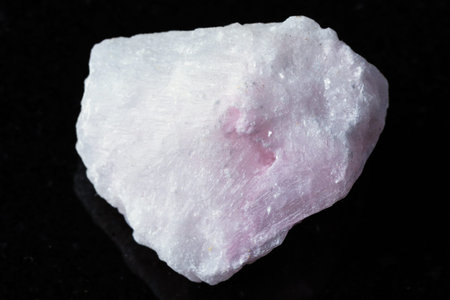sample of raw pink aragonite mineral on black granite background close up