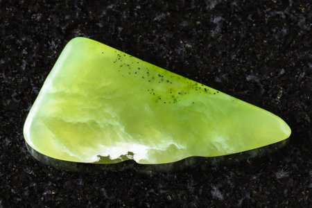 sample of polished vesuvianite mineral on black granite background close up from Yakutia, Russiaの写真素材