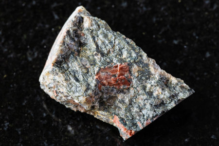 sample of raw gneissoid granite rock on black granite background close up from Karelia, Russiaの写真素材