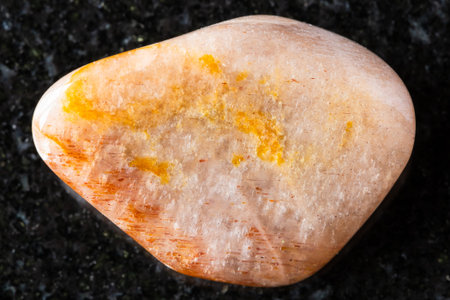 sample of polished iridescent feldspar mineral on black granite background close up from Madagascar
