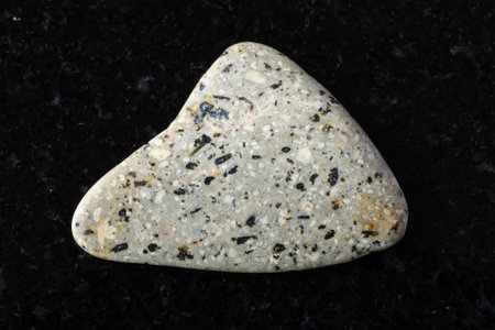 sample of polished andesite rock on black granite background close up from Crimeaの写真素材