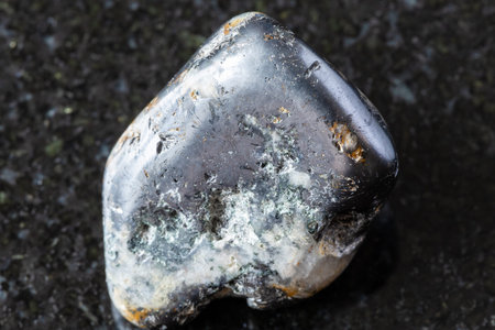 sample of polished cleiophane and mushketovite rock on black granite background close up from...