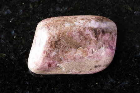 sample of tumbled pyroxmangite rock on black granite background close up from Colorado, USAの写真素材