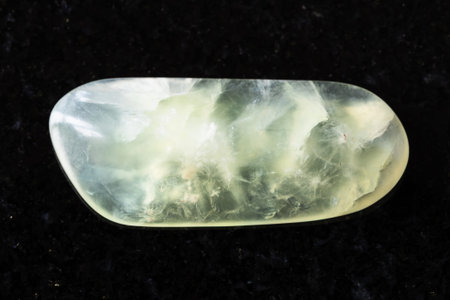sample of tumbled vesuvianite mineral on black granite background close up