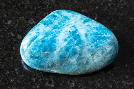 sample of polished apatite rock on black granite background close up from Brazil