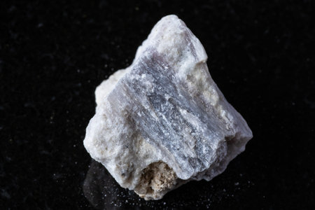 sample of rough rubellite crystal in rock on black granite background close up