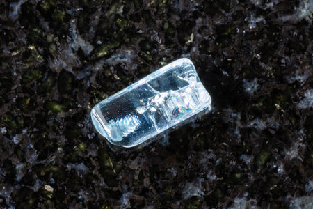 sample of rolled aquamarine crystal on black granite background close up