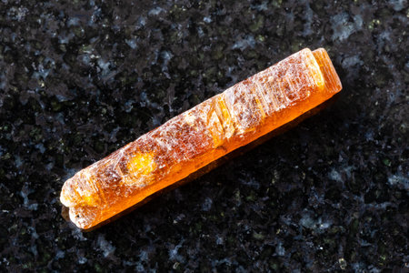 sample of rough orange kyanite crystal on black granite background close up from Tanzania