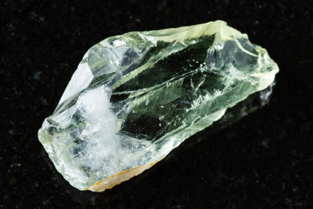sample of raw prasiolite rock on black granite background close up