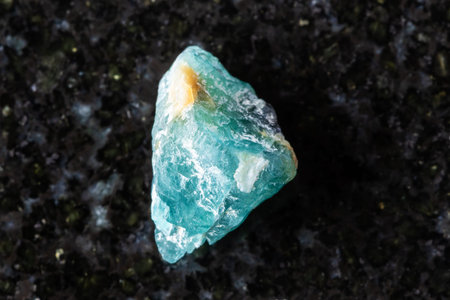 sample of unworked grandidierite crystal on black granite background close up from Madagascar