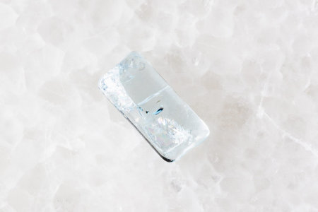 sample of tumbled aquamarine crystal on white marble background close up