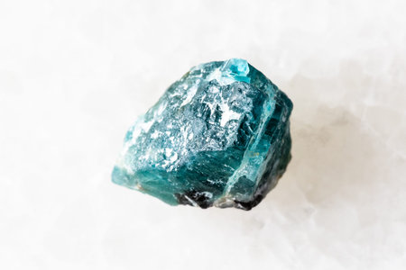sample of rough grandidierite crystal on white marble background close up from Madagascar
