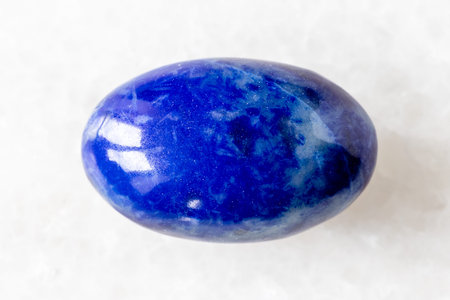 sample of polished lapis lazuli mineral on white marble background close up from Badakhshan,...
