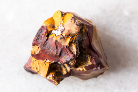 sample of raw colorful mookaite rock on white marble background close up