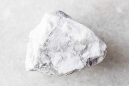 sample of raw howlite rock on white marble background close up