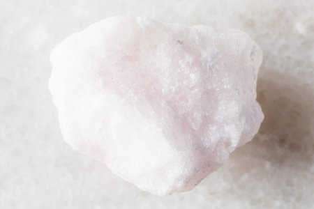 sample of raw pink aragonite mineral on white marble background close up