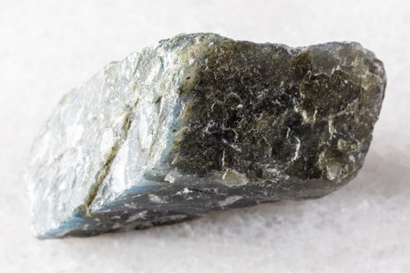 sample of rough labradorite rock on white marble background close up from Madagascar