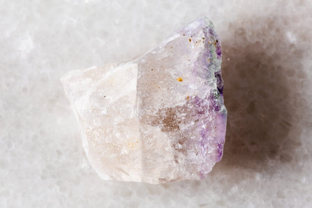 sample of unpolished fluorite mineral on white marble background close up
