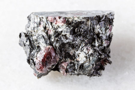 sample of raw red almandine garnets in rock on white marble background close up from Karelia, Russia