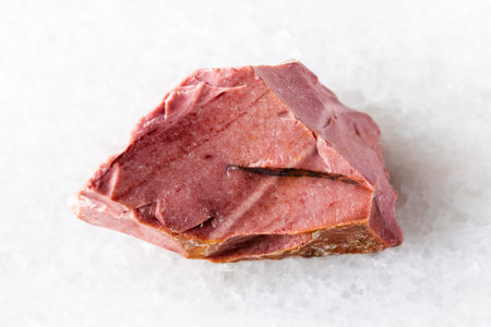sample of raw pink mookaite mineral on white marble background close up