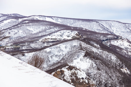 above view of snow-covered hills in Petropavlovsk-Kamchatsky city from Mishennaya sopka on overcast...