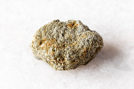 sample of unworked pyrite mineral on white marble background close up