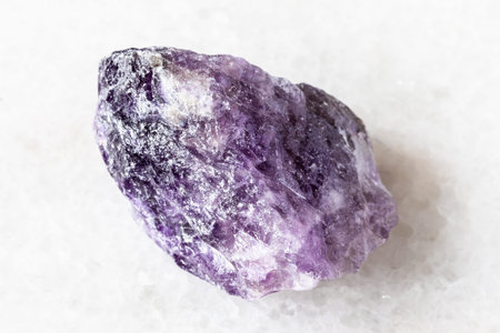 sample of rough amethyst rock on white marble background close up