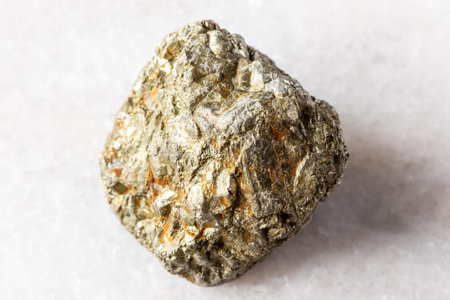 sample of rough pyrite rock on white marble background close up