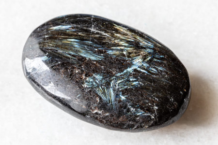 sample of polished nuummite rock on white marble background close up from Greenland