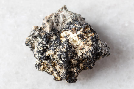 sample of raw cryptomelane mineral on white marble background close up from Kola Peninsula, Russia