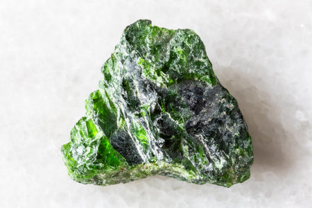 sample of raw chrome diopside mineral on white marble background close up from Yakutia, Russia