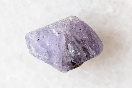 sample of raw tanzanite mineral on white marble background close up from Tanzania